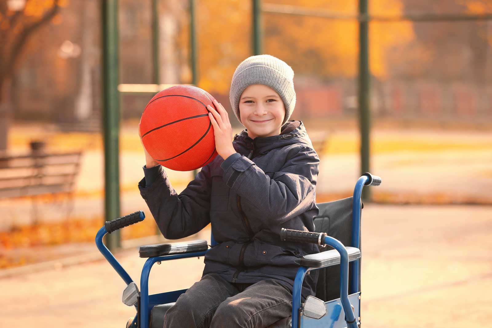 Little boy in wheelchair with ball on playground