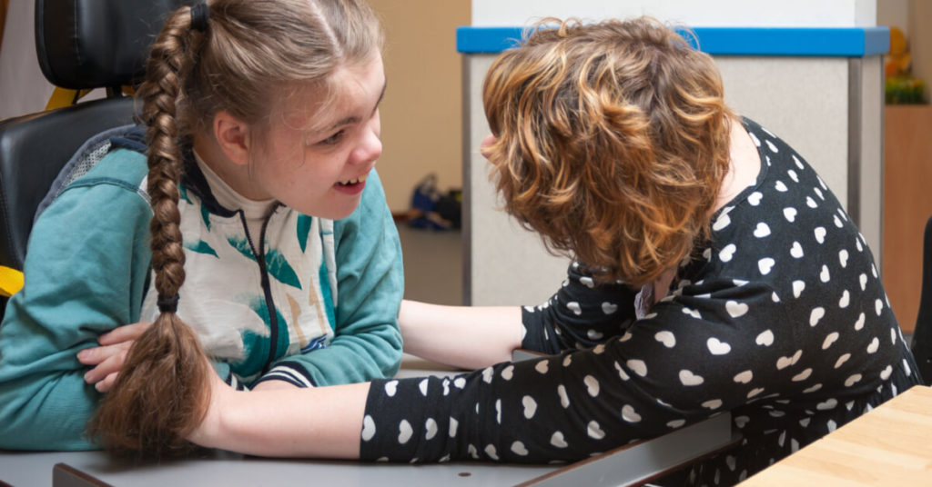 Special needs carer making contact with a disabled child in a wheelchair / Disabled person in a wheelchair having fun with a care assistant